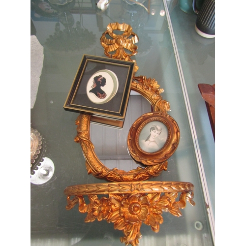 1392 - A gilt floral wall hanging mirror with shelf, Modes de Paris plaque and a silhouette (3)