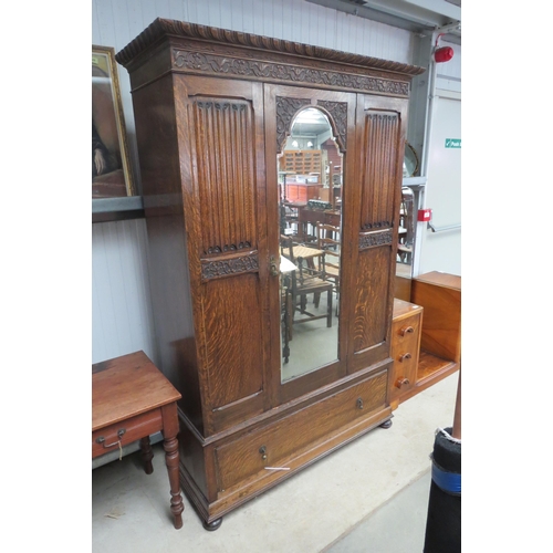 2118 - A 1920's oak linen press wardrobe with carved detail and linen fold doors and base