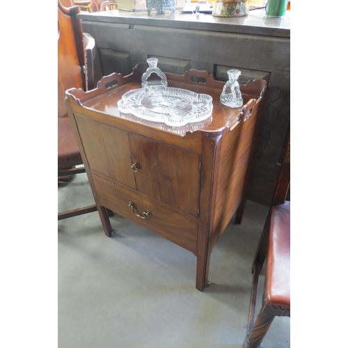 2151 - A George III mahogany nightstand, the gallery top with fret handles over a two door cupboard and sin... 