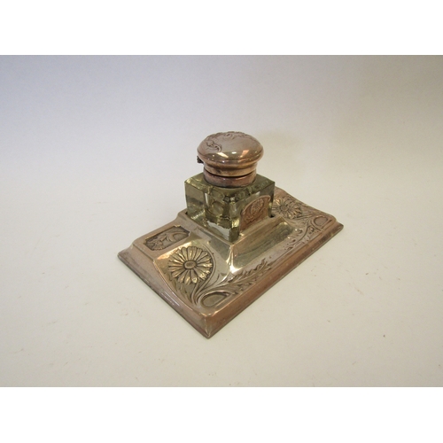 1278 - A Continental white metal and glass inkwell and stand with embossed floral decoration (marks rubbed)... 