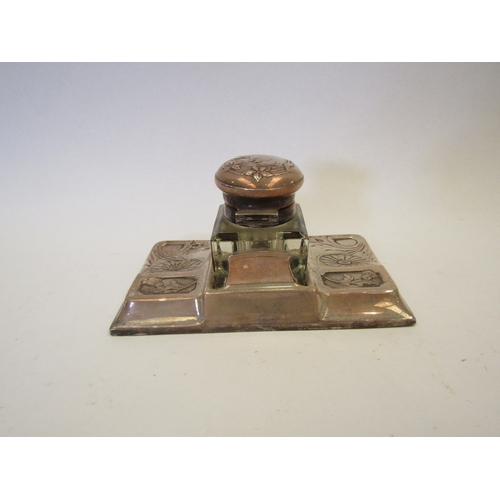 1278 - A Continental white metal and glass inkwell and stand with embossed floral decoration (marks rubbed)... 