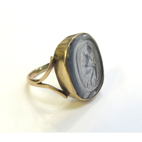 9316 - A gold intaglio ring of a seated man with sword, stamped 9ct, 20mm x 17mm. Size S, 6g