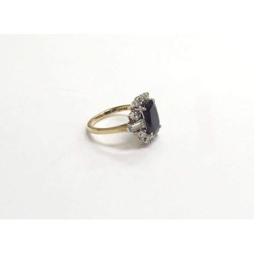 9137 - A sapphire and diamond cluster ring, the central sapphire 10mm x 7mm framed by brilliant cut diamond... 