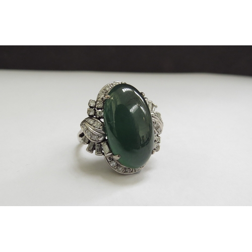 9071 - A large oval cabochon jade and diamond ring, the jade 20mm x 12mm framed by baguette and round cut d... 