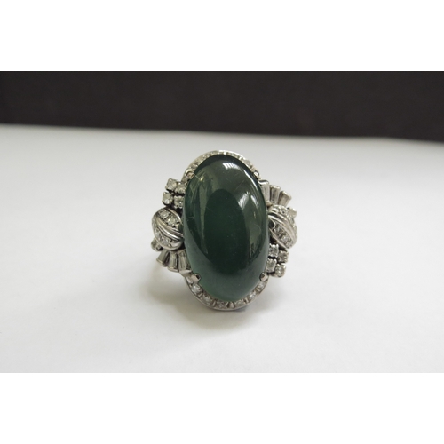 9071 - A large oval cabochon jade and diamond ring, the jade 20mm x 12mm framed by baguette and round cut d... 