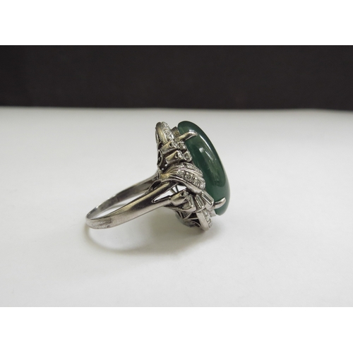 9071 - A large oval cabochon jade and diamond ring, the jade 20mm x 12mm framed by baguette and round cut d... 