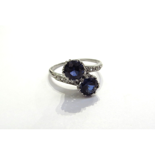 9144 - A sapphire and diamond crossover ring the two round cut sapphires, 5mm in diameter with diamond set ... 