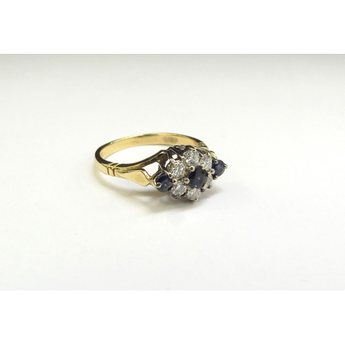 9302 - An 18ct gold sapphire and diamond daisy ring, the flower flanked by sapphires. Size O, with spacers,... 