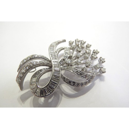 9276 - A diamond encrusted brooch as a floral spray of round brilliant cut diamonds with a baguette cut dia... 