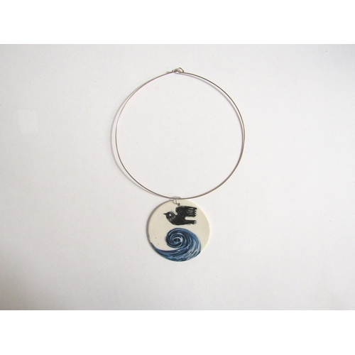 7258 - A porcelain plaque pendant on a white metal torc, hand painted with bird and wave detail. 7cm diamet... 