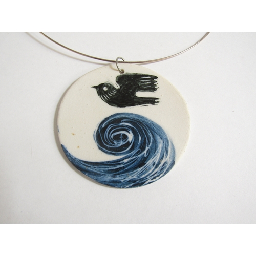 7258 - A porcelain plaque pendant on a white metal torc, hand painted with bird and wave detail. 7cm diamet... 