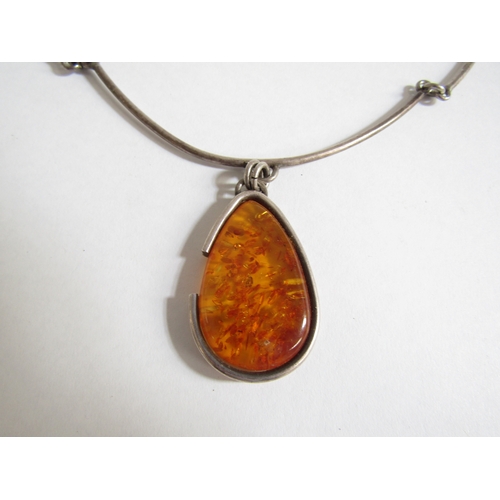 7256 - A silver torc necklace with an amber teardrop pendant