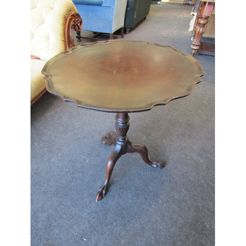 1100 - A stained mahogany occasional table with piecrust top, wrythen column, tripod legs on ball and claw ... 