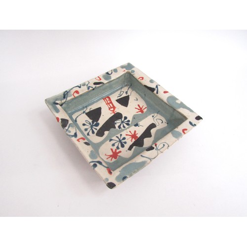 7076 - JOHN MALTBY (1936-2020): A studio pottery square dish with painted motifs in blue, black and red. Pa... 