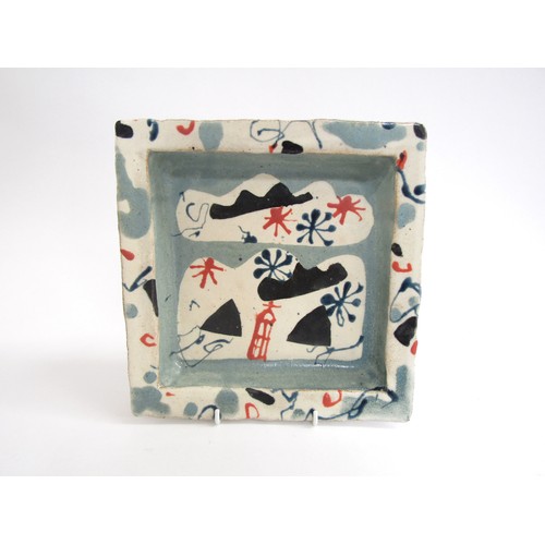 7076 - JOHN MALTBY (1936-2020): A studio pottery square dish with painted motifs in blue, black and red. Pa... 