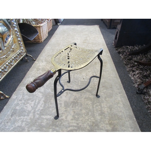 1044 - An ornate brass trivet on an iron stand with a mahogany turned handle