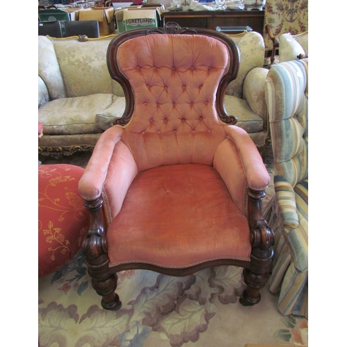 1135 - A circa 1850 carved mahogany button backrest library armchair with salmon pink upholstery, the scrol... 