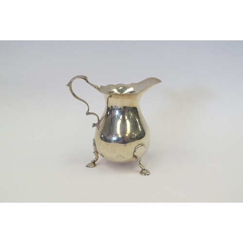 1324 - A silver cream jug, wavy edge, scroll handle, raised on pad feet, London 1933, 101g