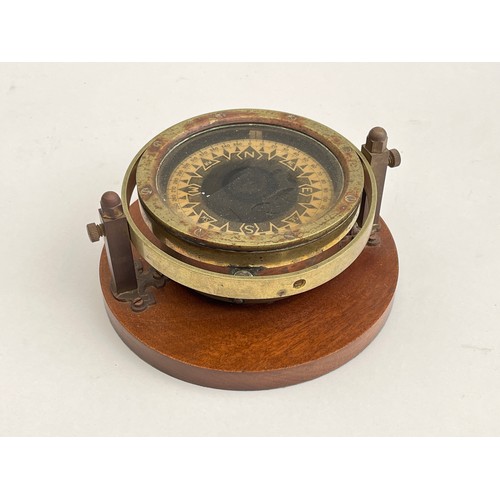 8031 - A brass cased gimballed compass, no visible maker, mounted on hardwood plinth, 13cm diameter case