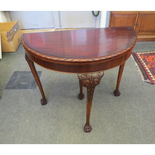 1102 - A demi-lune carved edge top games table, the baize lined circular top over a pull-out rear support l... 