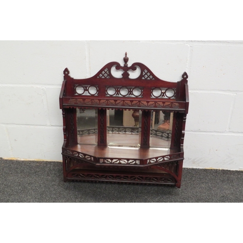 1106 - A Victorian mahogany fret carved three tier wall shelf with triple mirror and finial decoration, 65c... 