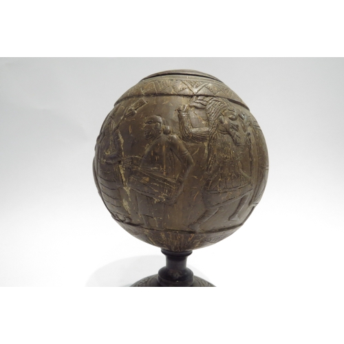 4427 - A carved coconut shell decorated with tribal scenes, lidded, 20cm tall  (R)  £40