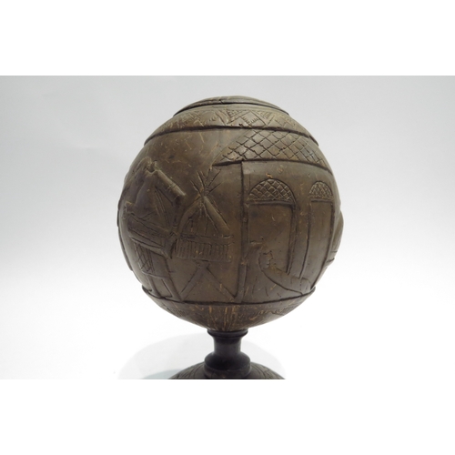 4427 - A carved coconut shell decorated with tribal scenes, lidded, 20cm tall  (R)  £40