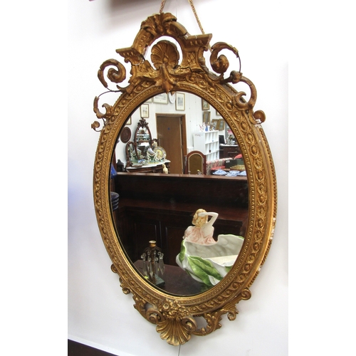 4148 - A 19th Century gilt gesso oval wall mirror, scrolled detail, shell relief, some losses, 89cm x 56cm