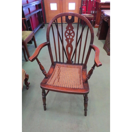 4177 - A hooped stick back Windsor armchair with wheel back splat over a cane seat on turned legs, united b... 