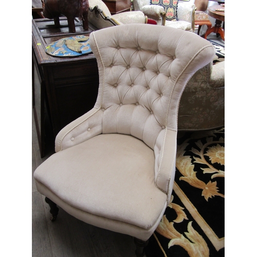 4255 - A late Victorian button back armchair with champagne upholstery the outswept back rest over a bowed ... 