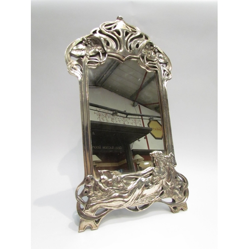 4068 - An Art Nouveau style metallic effect easel-back table mirror, the base with relief of reclining semi... 