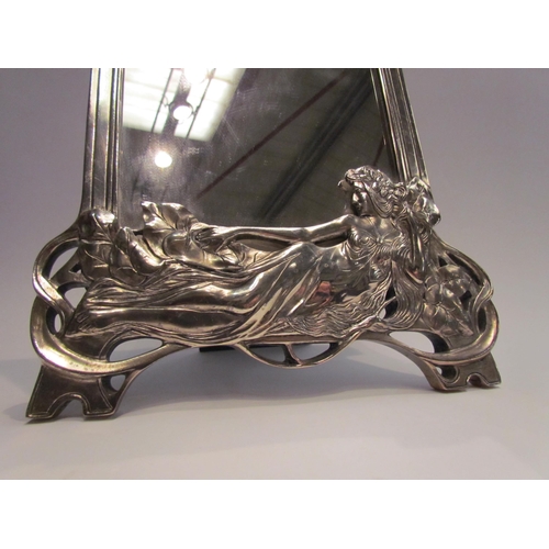 4068 - An Art Nouveau style metallic effect easel-back table mirror, the base with relief of reclining semi... 