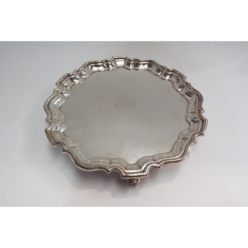 4346 - A George V silver salver, centred by a monogram, with piecrust rim and three gnarled feet.  Sheffiel... 