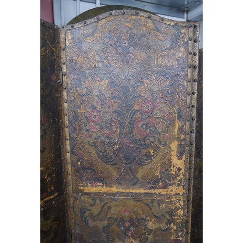 2111 - A distressed leather four panel screen, arch top, floral decoration, each panel 182cm x 52cm