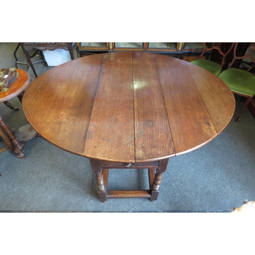 1028 - An 18th Century pegged oak oval plank top gate-leg dining table, the rising leaves over a single end... 