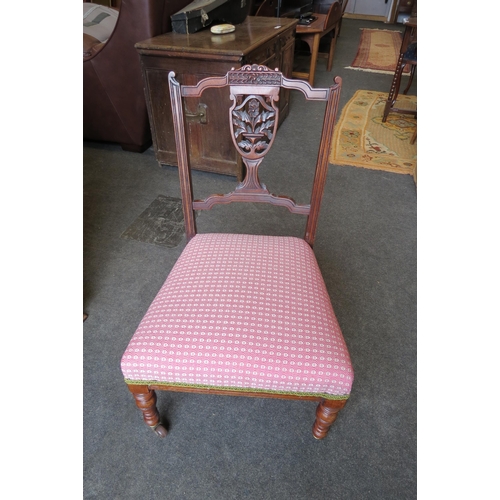 1140 - A Victorian nursing chair with floral pierced and carved back splat on ceramic castors