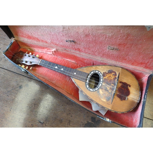 1142 - A cased mandolin with mother-of-pearl inlay and bone tuning pegs, a/f