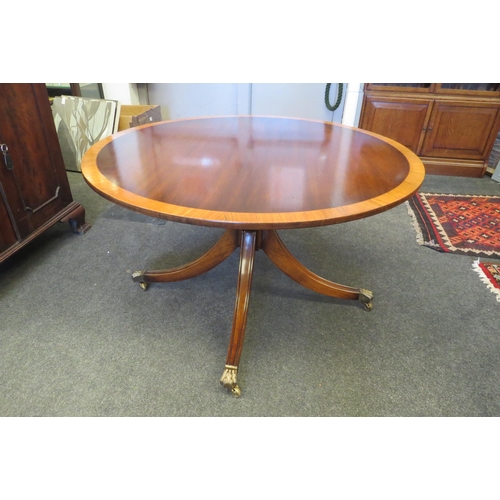 2233 - A circular top table on outswept legs with brass lion paw feet on brass cup castors   (R) £0