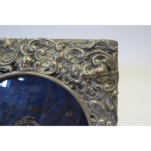 1273 - A silver photograph frame, pierced design of cherubs amongst foliage, 16cm tall, marks indistinct