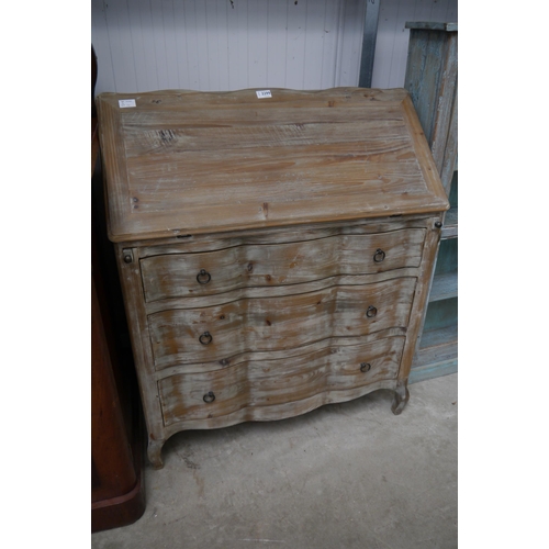 2299 - A limed pine bureau, the fall front over a serpentine front set with three drawers