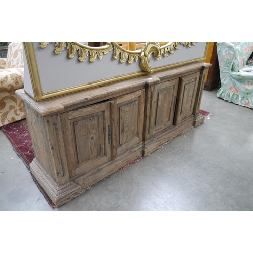 2438 - A rustic pine low sideboard, four cupboard doors, plinth base