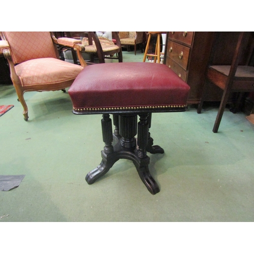 4238 - A late Victorian ebonised revolving and height adjustable piano stool, the square seat on reeded col... 