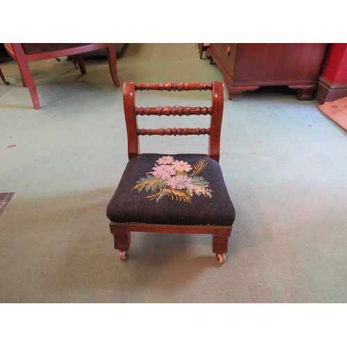 4244 - A Victorian child's chair with spindle back rails and tapestry floral seat on ceramic castors