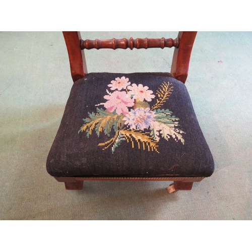 4244 - A Victorian child's chair with spindle back rails and tapestry floral seat on ceramic castors