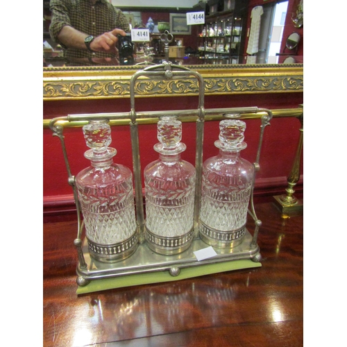 4143 - An EPNS three bottle tantalus with key: the diamond and leaf cut decanters in a stand with top lock