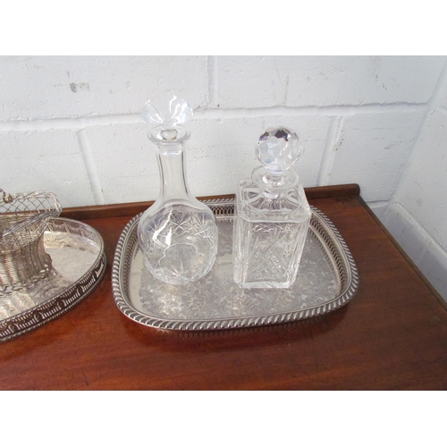 1210 - Two plated galleried trays, a wirework basket and two cut glass decanters (5)