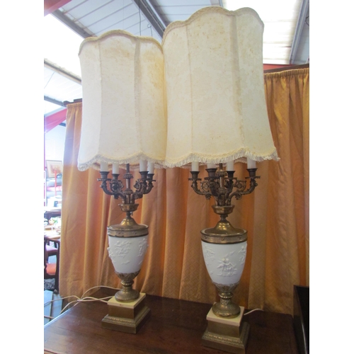 1297 - A pair of American style four candle table lamps, cherubic bodies and ornate gilt scrolled arms on g... 