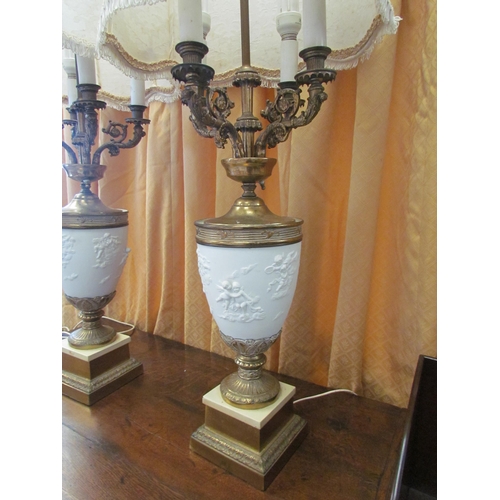 1297 - A pair of American style four candle table lamps, cherubic bodies and ornate gilt scrolled arms on g... 