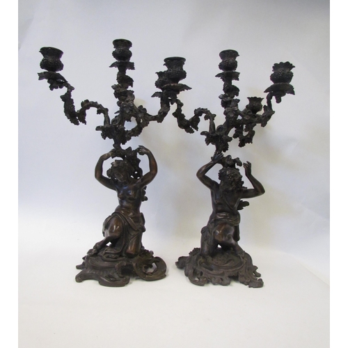 1634 - A pair of early 19th Century bronze figural three branch, four light candelabra in the Rococo style,... 