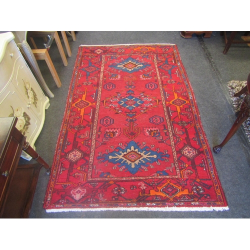 1677 - An Iranian wool rug, deep red ground with three central medallions, multiple geometric borders, 207.... 